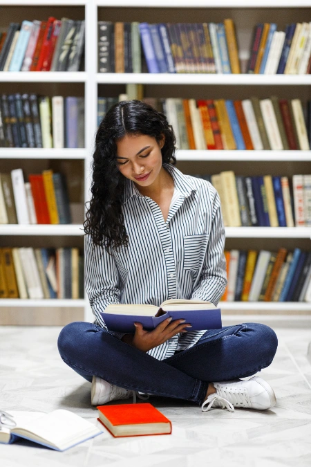 Mujer estudiante leyendo un libro en biblioteca